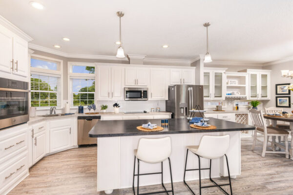 This open kitchen overlooks the living room.. the white cabinets are accented by the black countertop on the large island. The adjoining dinging room has a build in hutch with a wine rack